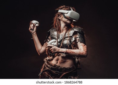 Portret van een barbaarse vrouw uit Noord gekleed in middeleeuws pantser poseren in donkere achtergrond met virtual reality headset.