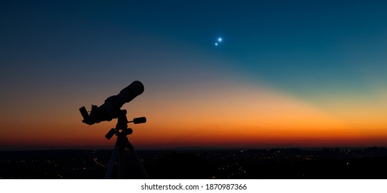 Silhouet van een astronomietelescoop met schemerhemel.