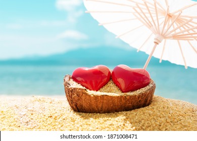 Two red hearts under beach umbrella, blue sky and sea in background. Romantic trip for couple in love concept. Valentine's Day, 14 February symbol. Copy space