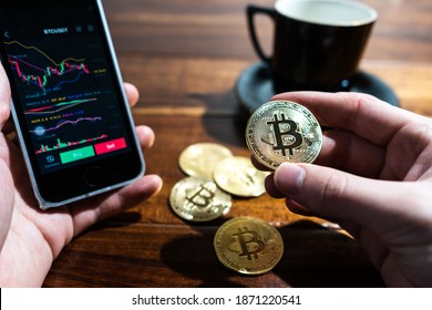 画面にビットコイン取引チャートが表示されたスマートフォン。金のビットコイン キャッシュ コインを手に保持します。暗号通貨取引所での取引。