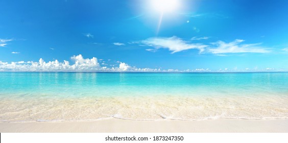Schöner Sandstrand mit weißem Sand und rollender ruhiger Welle des türkisfarbenen Ozeans an einem sonnigen Tag auf weißen Hintergrundwolken im blauen Himmel. Insel auf den Malediven, farbenfrohe, perfekte Panorama-Naturlandschaft.
