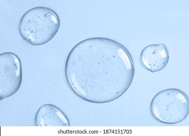 青色の背景に泡と液体の透明なゲルの滴