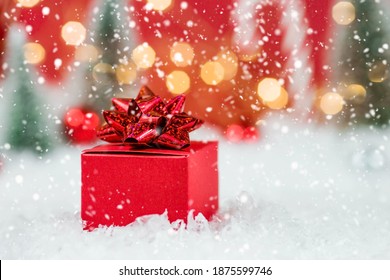 Banner. Weihnachtsrote Geschenkbox in einer roten verschneiten Landschaft auf einem Bokeh-Hintergrund. Platz für Text. Das Konzept der Lieferung von Geschenken und Grußkarten frohes neues Jahr. Nahansicht.