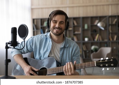 笑顔のミレニアル世代の白人男性歌手または作曲家のポートレートは、ホームスタジオでギターレコードの新しいシングルを保持しています。幸せな若い 20 代の男性アーティストは、電気楽器で曲を演奏します。趣味のコンセプト。