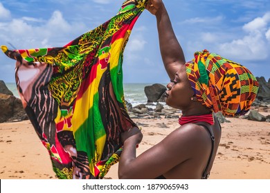 Tanzende Ghana-Frau am schönen Strand von Axim, in Ghana Westafrika. Kopfschmuck in traditionellen Farben aus Afrika.