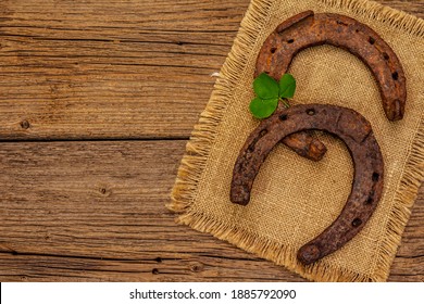 Dua tapal kuda besi tuang dari besi tuang, daun semanggi segar. Simbol keberuntungan, konsep Hari St.Patrick. Latar belakang kayu antik, aksesoris kuda