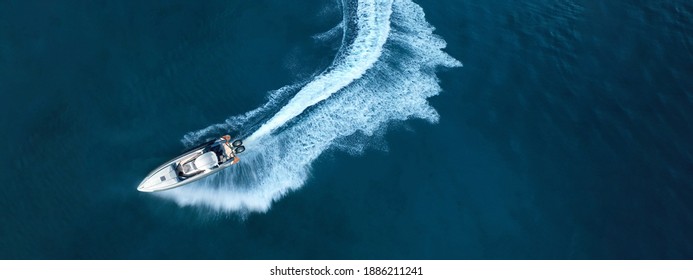 Luftdrohne von oben nach unten, ultrabreites Foto eines aufblasbaren Power-Rib-Bootes, das in der Abenddämmerung extreme Manöver in der Mittelmeerbucht mit tiefblauem Meer durchführt