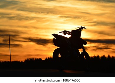 Gambar indah matahari terbenam dengan siluet sepeda motor