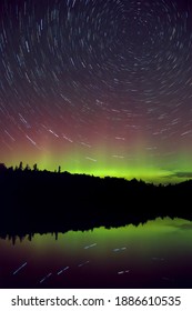 スター トレイルとカラフルな緑と紫のオーロラ (オーロラボレアリス) カナダ、オンタリオ州アルゴンキン州立公園の湖の上の夜空