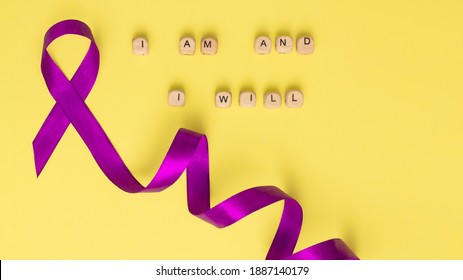 Houten kubussen met tekst van de slogan van Wereldkankerdag ik ben en ik zal en een paars lint, op een gele ondergrond. Plat leggen. Banner