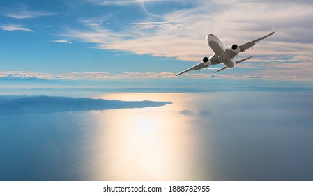 日没時に熱帯の海の上を飛ぶ飛行機