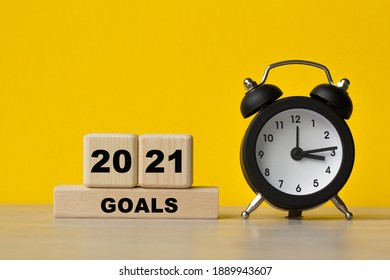 GOALS 2021 , text written on cubes, alarm clock on a yellow background. The concept of world business, marketing, finance.