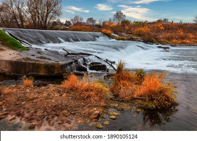 Herbstliche Landschaft. Wasserströme, aufgenommen mit Langzeitbelichtung, fallen auf einen künstlichen Damm. Künstliche Wasserfalllandschaft im Herbst.