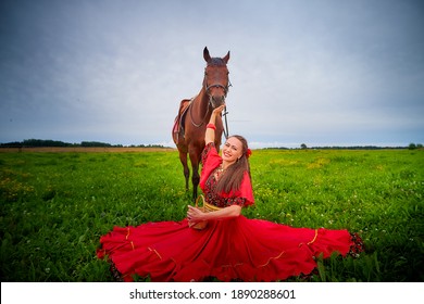 Mujer con un vestido gitano brillante e imagen con un caballo en un campo con hierba verde. Una modelo o actriz posando en la naturaleza con un animal de una granja y el cielo con nubes de fondo