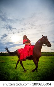 Mujer con un vestido gitano brillante e imagen con un caballo en un campo con hierba verde. Una modelo o actriz posando en la naturaleza con un animal de una granja y el cielo con nubes de fondo
