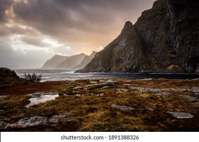 Å i Lofoten in Nordnorwegen, Berge, blaues Meer, Wolken und rosa Himmel, Wind, Wellen, im Herbst, im Archipel der Lofoten, dramatische Atmosphäre
