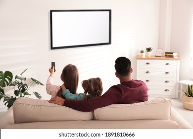 Familie ser tv på sofaen derhjemme, set bagfra
