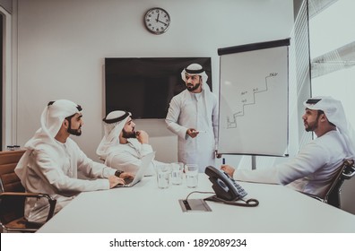 オフィスで働くアラビア人グループの映画のようなイメージ。屋内で事業計画を立てるドバイの伝統的な衣装を着た 4 人の男性
