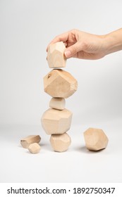 Tumi-ishi puzzle game. A woman or a girl places her hand on another block of wood on top of an unstable tower. The process of the game. Stones for Rock Balance.