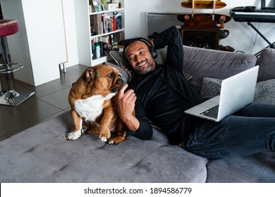 ソファでくつろぎ、犬の隣で映画を見ている中年男性