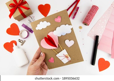 バレンタイン・デー。バレンタインデーのカードを作るための指示。ステップ 10 ハートと雲をベースに接着します。ポストカードが完成しました