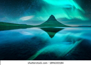 Aurora borealis Northern lights over Kirkjufell mountain volkano. Amazing night scene near famous Kirkjufell waterfall, Iceland. Landscape photography