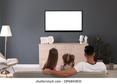 Familie ser tv på sofaen derhjemme, set bagfra
