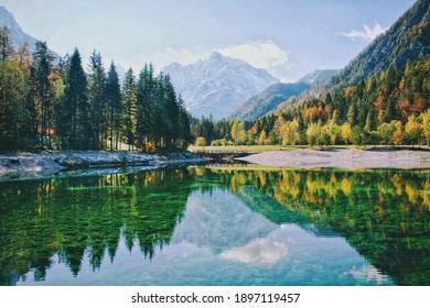 緑のヤスナ湖、クランスカゴーラの穏やかな海に映る、日の光の中の秋のアルプス山脈。スロベニア。