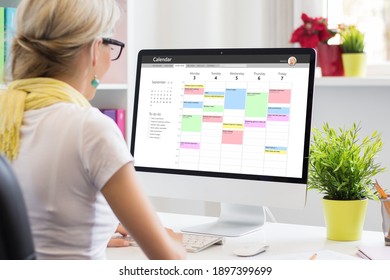 オフィスのコンピューターでカレンダー アプリを使用している女性