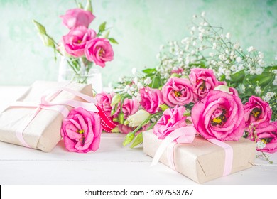 Schöne Frühlingsblumen auf weißem Holzhintergrund. Festliche Blumenkomposition mit Kraftpapier-Geschenkboxen. Valentinstag, Frauentag, Muttertagsgrußkarte. Ansicht von oben flach liegend
