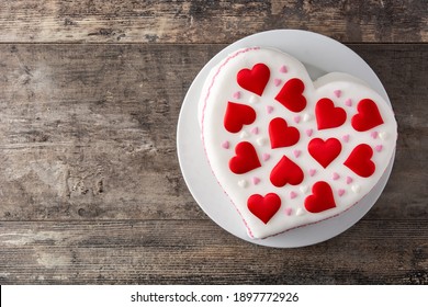 Herzkuchen zum Valentinstag, Muttertag oder Geburtstag, dekoriert mit Zuckerherzen auf Holztisch