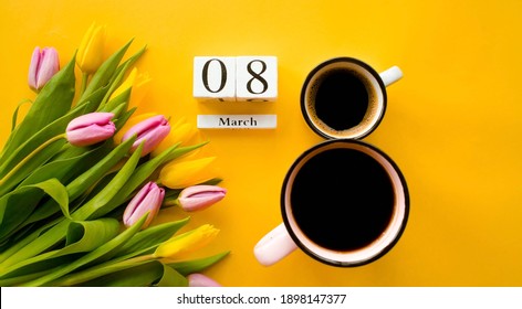 Two cups of coffee, a delicate bouquet of tulips and numbers. Greeting card for Women's Day on March 8. Fashionable yellow background. March 8 and the concept of "women's day".