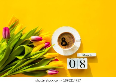 Banner.A cup of hot, morning coffee and a bouquet of yellow-lilac tulips on a bright yellow background. View from above. Close-up. Copy space for text. The concept of holidays and good morning wishes.