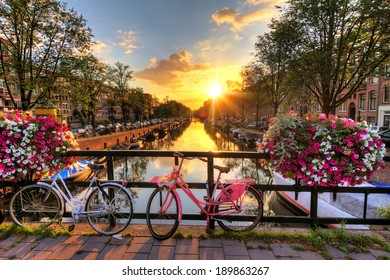 Beautiful sunrise over Amsterdam, The Netherlands, with flowers and bicycles on the bridge in spring