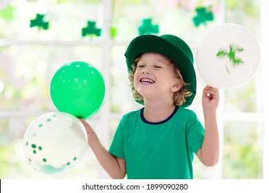 Keluarga merayakan Hari St. Patrick. Liburan Irlandia, budaya dan tradisi. Anak-anak mengenakan topi dan janggut leprechaun hijau dengan bendera Irlandia dan daun semanggi. Anak-anak bersenang-senang di pesta St Patrick.