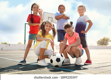 Niños lindos con pelota de fútbol en la cancha deportiva en un día soleado. Campamento de verano