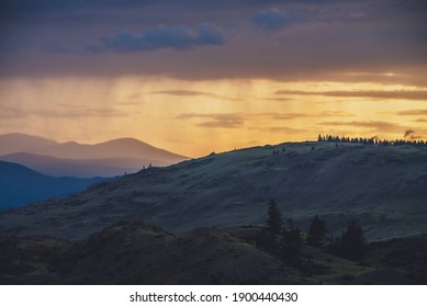 Atmospheric landscape with silhouettes of mountains with trees on background of vivid orange blue violet dawn sky. Colorful nature scenery with sunset or sunrise of illuminating color. Sundown paysage