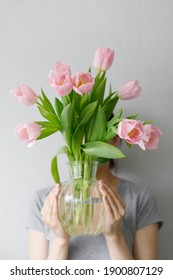girl holding pink tulips in a glass vase against a gray wall, florist, bouquet of tulips, pink tulips, gift, flowers as a gift, March 8, Valentine's day, birthday wife, date, flowers for a woman