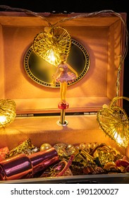 暗い背景に金の花輪で飾られた小さな甘いバレリーナとバラのオルゴール