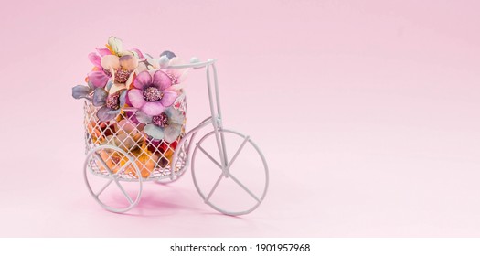 Internationaler Frauentag. Banner, Flyer, Postkarte kleines Fahrrad mit Blumenstrauß. Blumen und ein altes Fahrrad auf einem rosa Hintergrund. Blumenlieferdienst. Online-Bestellung in einem Blumenladen.