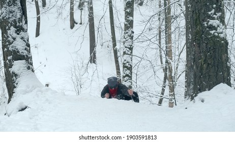 Man in red bandana and black, round glasses using two knives climbs snow covered mountain