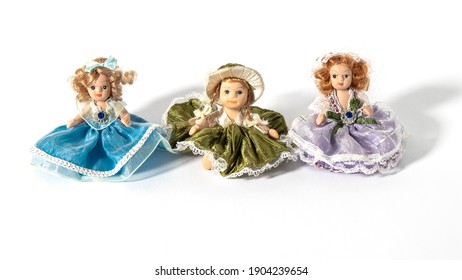 Tres hermosas muñecas de cerámica vintage diminutas vestidas como princesas sobre un fondo blanco. composición retra.