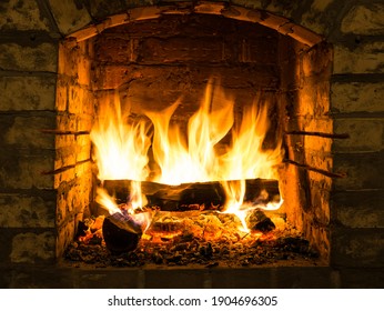 Verbrennen von Brennholz im Feuerraum des Kamins im Landhaus. Rustikaler Kochofen mit brennenden Holzscheiten.