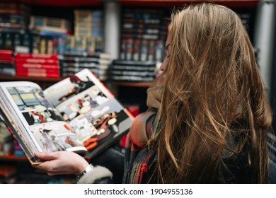 Eine schöne Frau in einem Buchladen hält ein offenes Comicbuch in den Halskrausen (das Buch ist verschwommen).