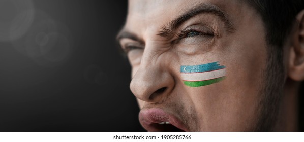 A screaming man with the image of the Uzbekistan national flag on his face.