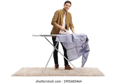 Full length portrait of a young man ironing a shirt and smiling at camera isolated on white background