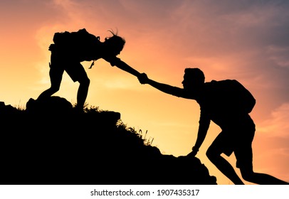 Dos escaladores ayudándose unos a otros hasta el borde de una montaña. Trabajo en equipo y concepto de fuerza física y mental.