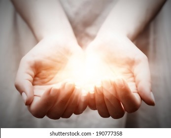 La luz en manos de mujer joven en forma de copa. Conceptos de compartir, dar, ofrecer, cuidar, proteger