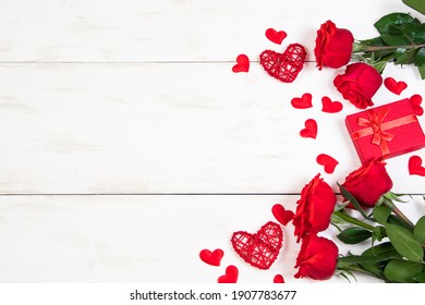 Roses rouges et coeurs sur fond de bois blanc. Saint Valentin, place au texte.