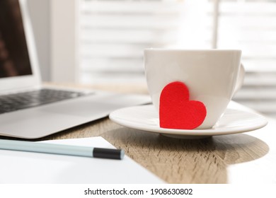 Cup with red heart on table, space for text. Valentine's day celebration